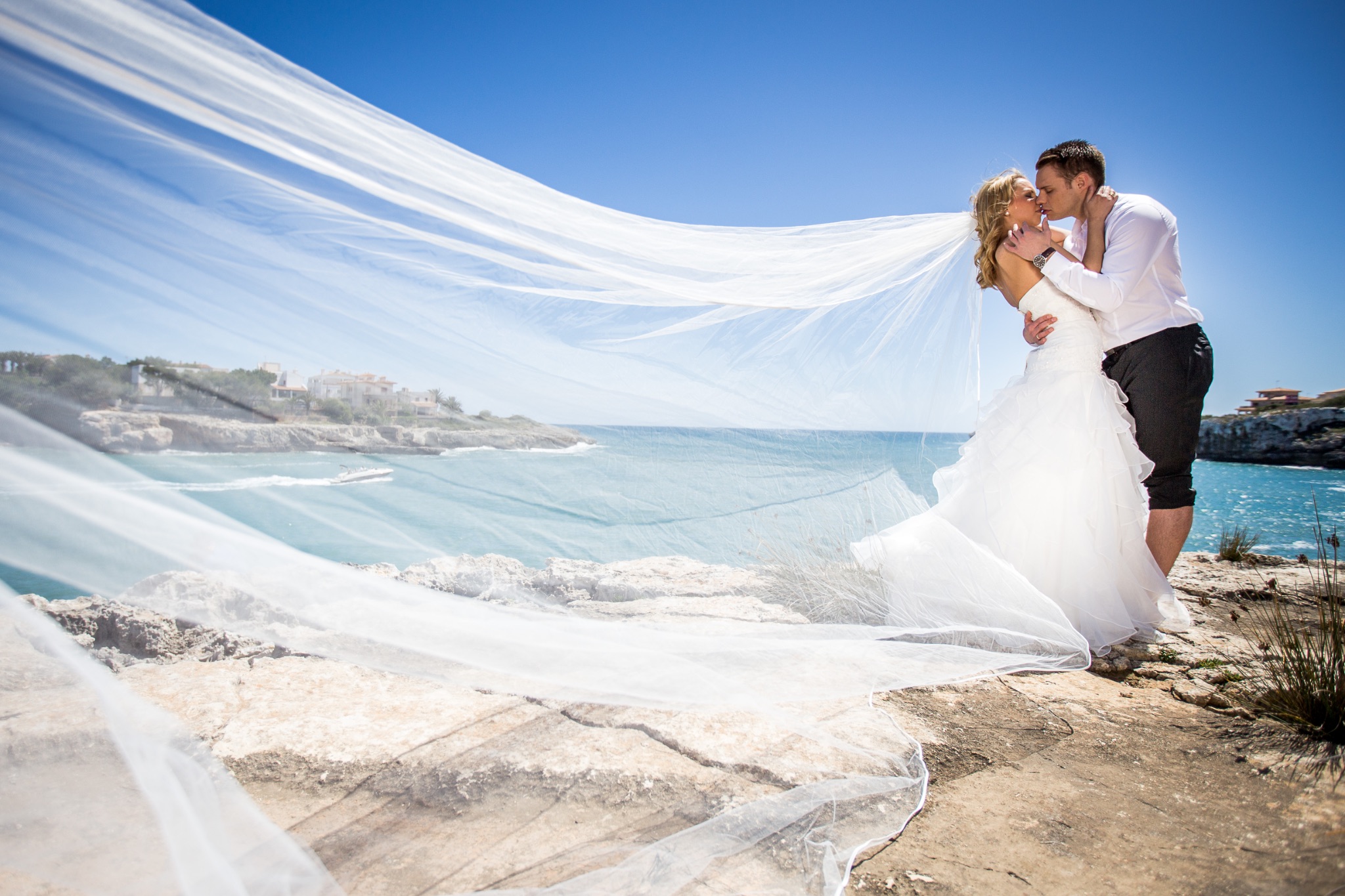 Afterwedding mallorca brautpaar kuesst sich schleier weht im wind