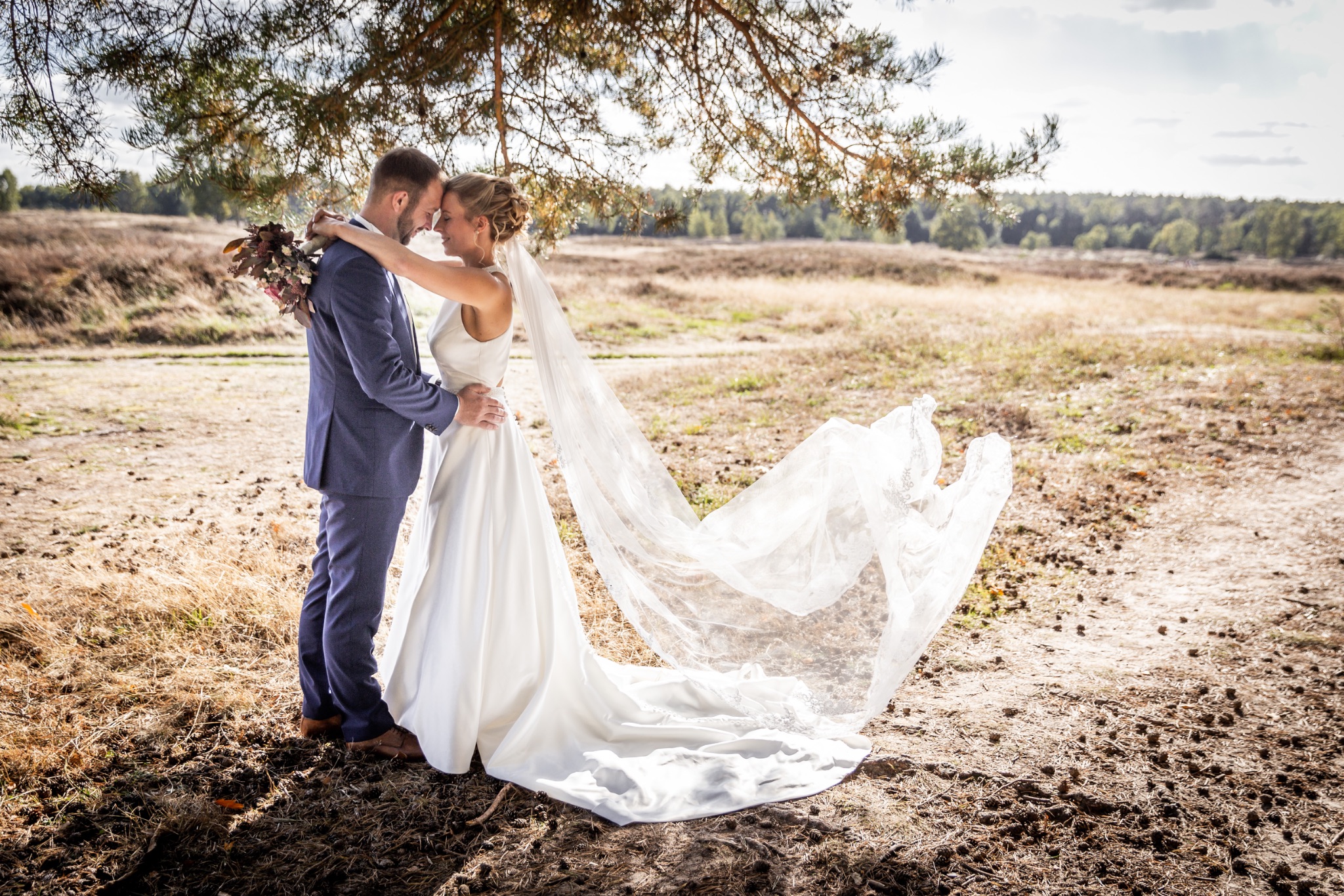 Hochzeitsportrait brautpaar in armen schleier weht im wind